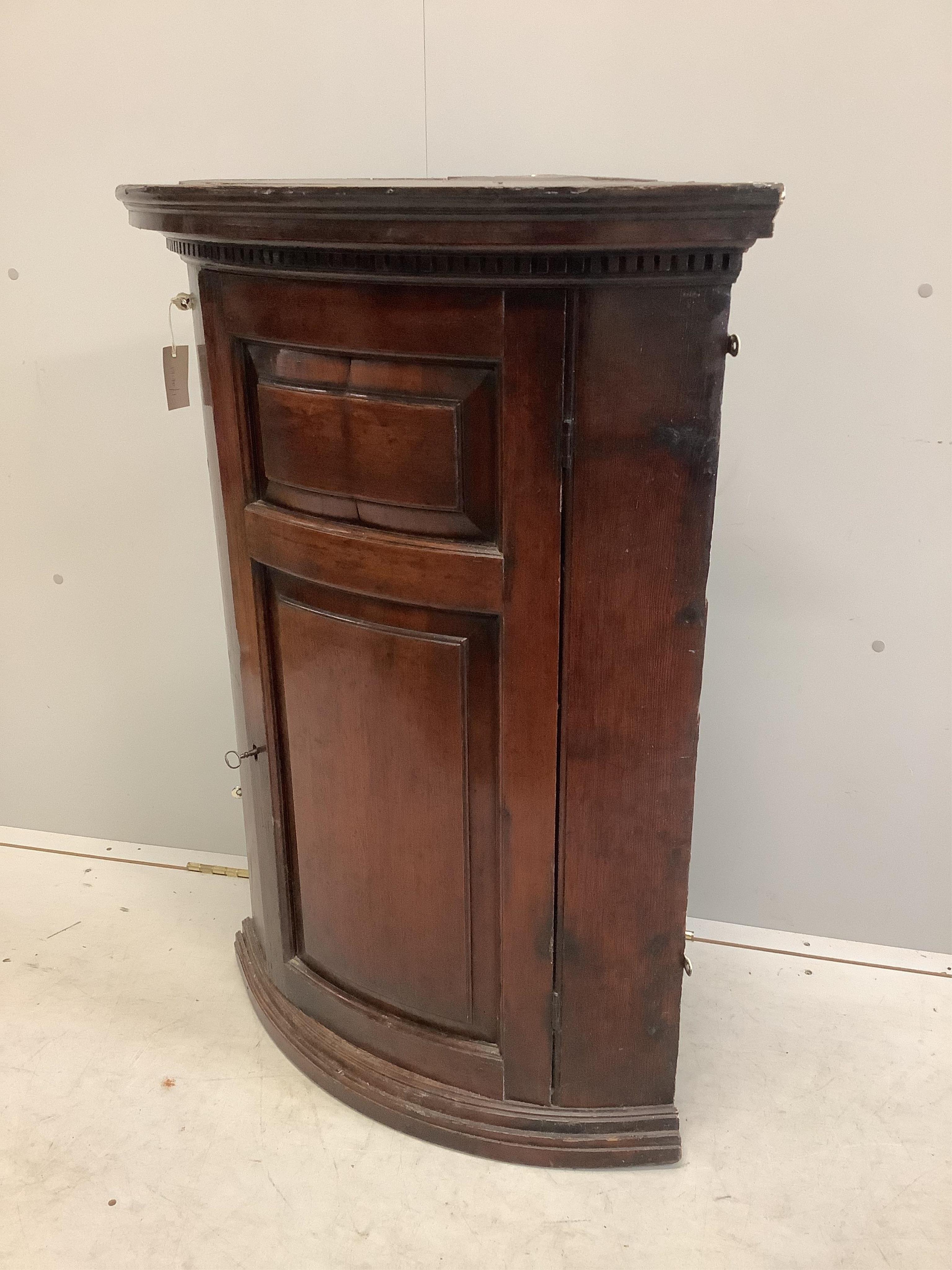 An 18th century pine bow front hanging corner cupboard, width 72cm, depth 46cm, height 101cm. Condition - fair to good